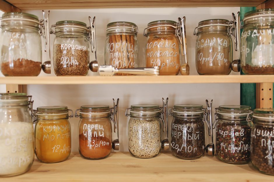 Wooden pantry shelves lined with clear glass jars of grains, spices, and dry ingredients.
